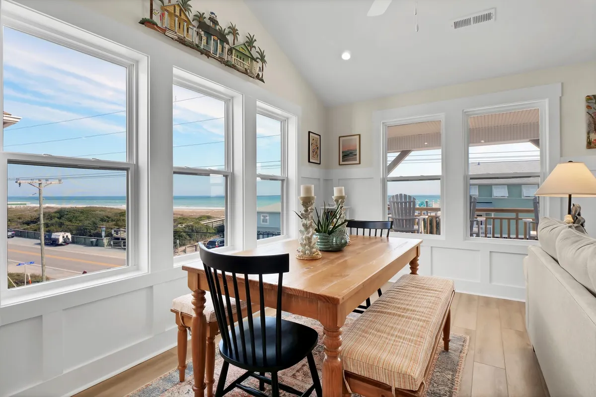 A dining table positioned to enjoy a breathtaking ocean view through the windows, with decorative accents on the table. The scene hints at memorable meals, board games, and sunset watching with family and friends.